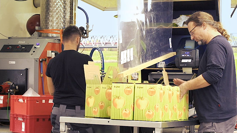Ralph Joos (pictured right) on the road: Here he is packing fresh juice in bag-in cardboard boxes.